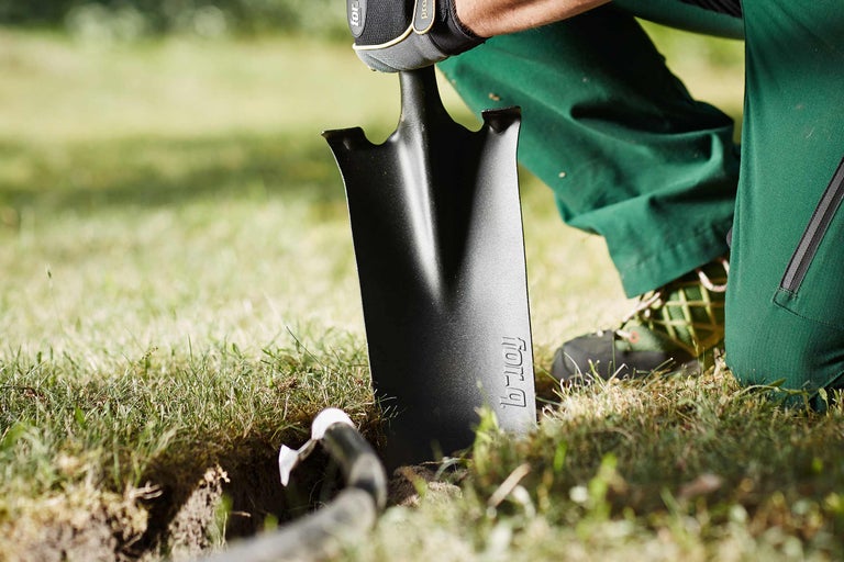 Une personne creuse un trou dans le jardin avec une bêche.