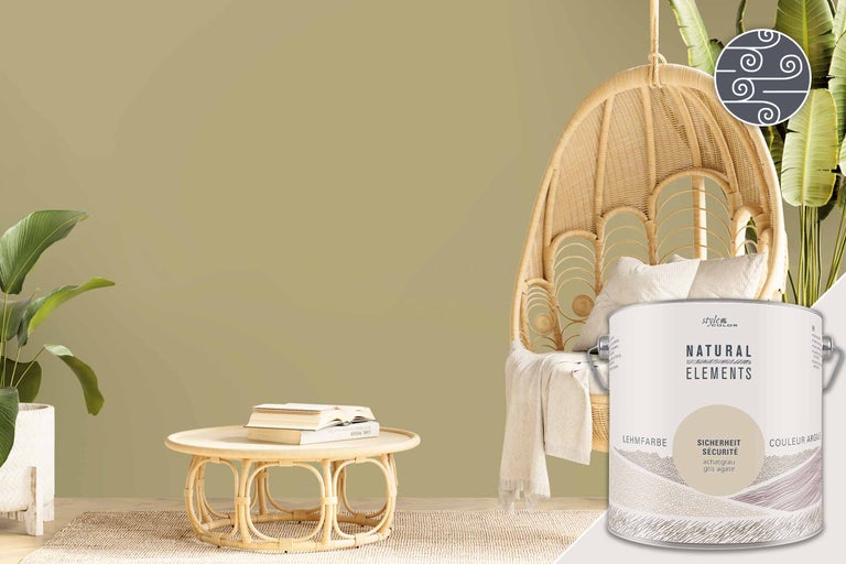 Ambiance de pièce avec un seau de peinture à l'argile, un fauteuil en rotin et une table