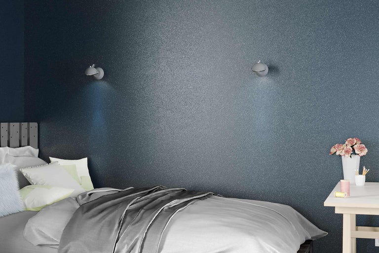Chambre à coucher avec lit, table de chevet et appliques murales devant un mur texturé
