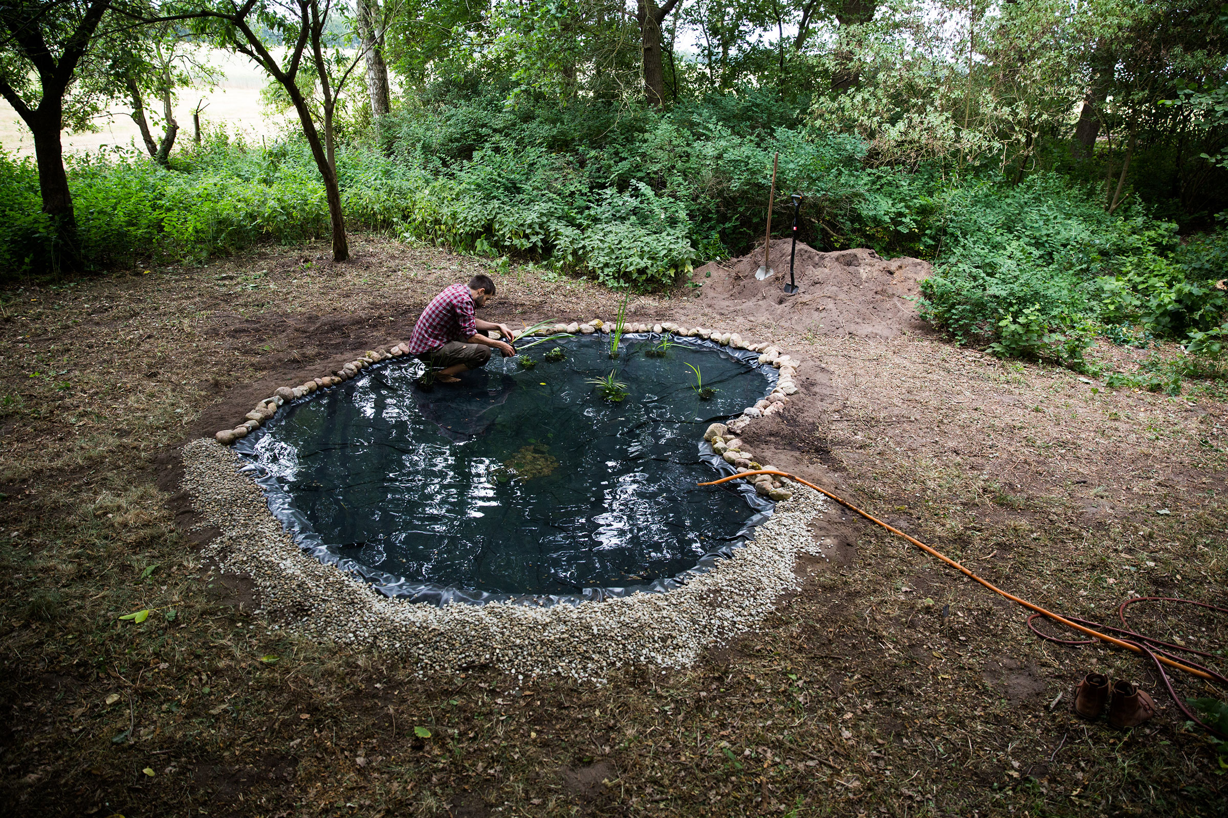 Construction d'un bassin de jardin avec bâche, pierres et plantations dans le jardin