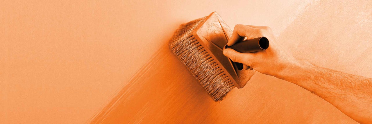 Person trägt eine Lasurbürste auf eine Wand auf