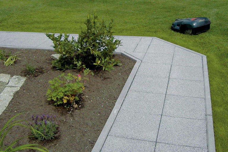 Chemin de jardin avec robot tondeuse à l'arrière-plan