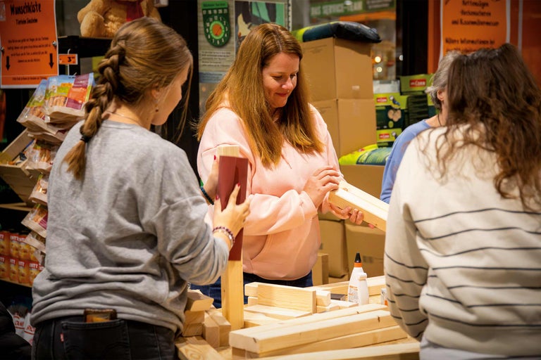 Des personnes construisent une boîte à souhaits avec des morceaux de bois et de la colle.