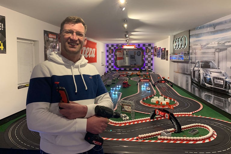 Mann mit Autorennbahn, Audi Logo und Carrera Logo im Hintergrund