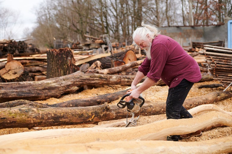 Homme coupant du bois avec une tronçonneuse à l'extérieur