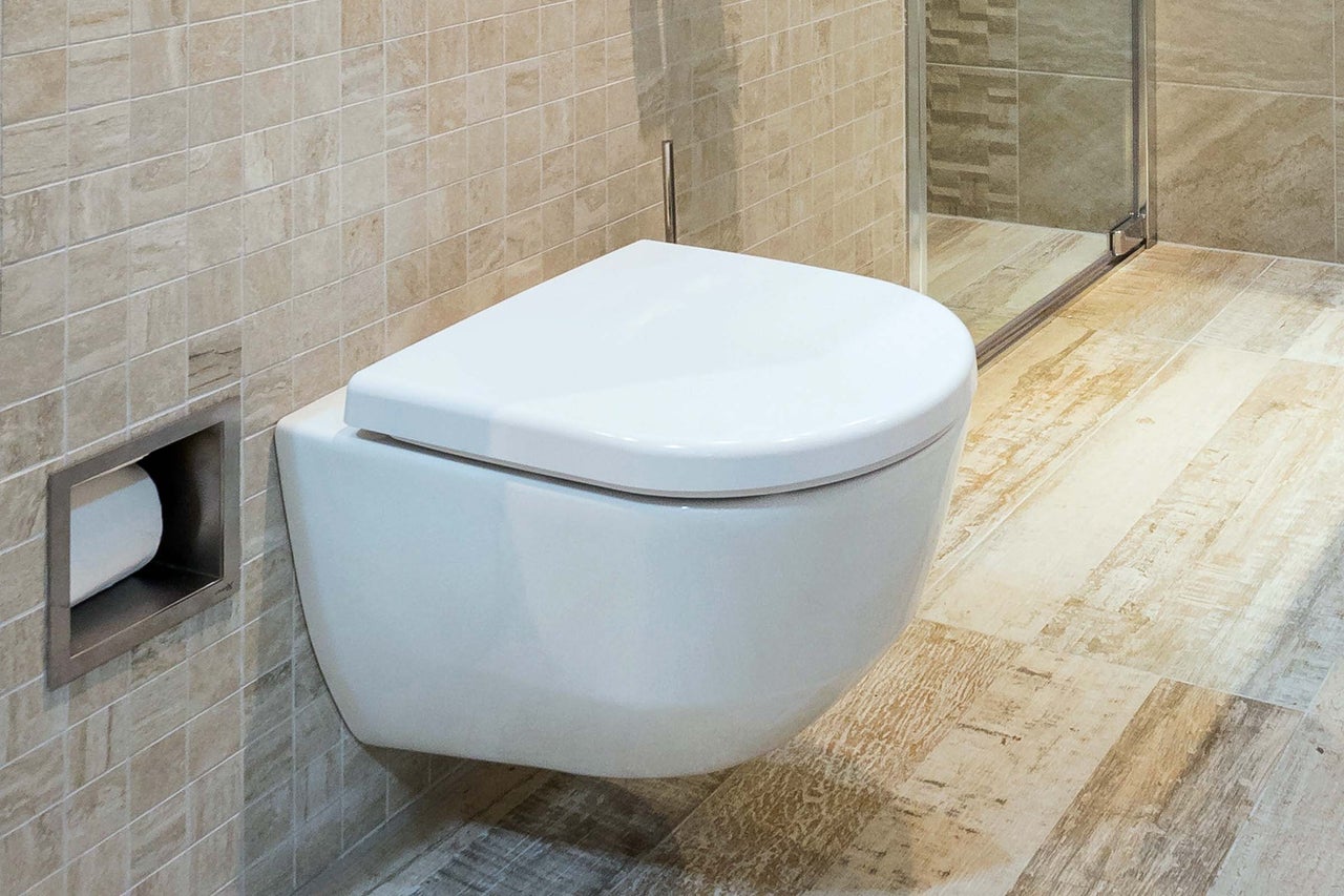 Modernes Badezimmer mit wandhängendem WC, Fliesenspiegel und eingebautem Toilettenpapierhalter
