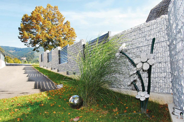 Gabionenzaun mit Ziergras und Metallkugel im Garten