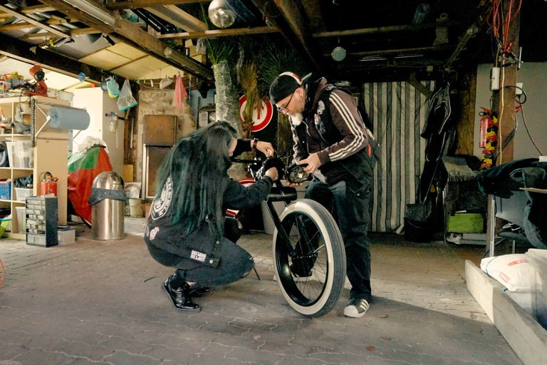 Zwei Personen reparieren ein Fahrrad in einer Garage.
