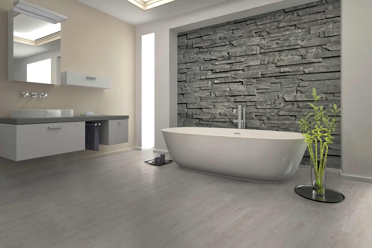 Salle de bains avec baignoire, meuble sous-lavabo, miroir et mur en pierre