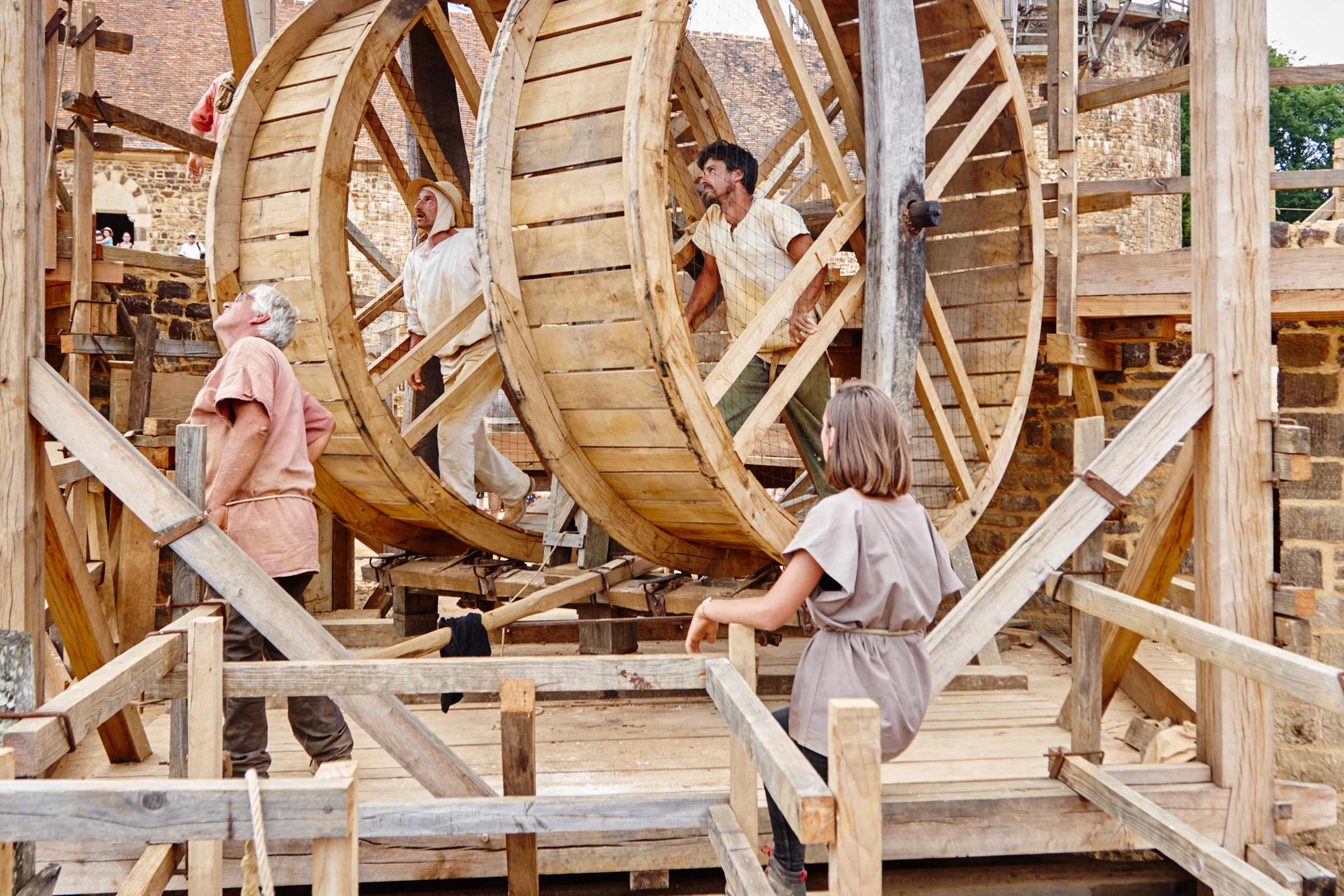 Scène avec des personnes travaillant sur une grande roue en bois
