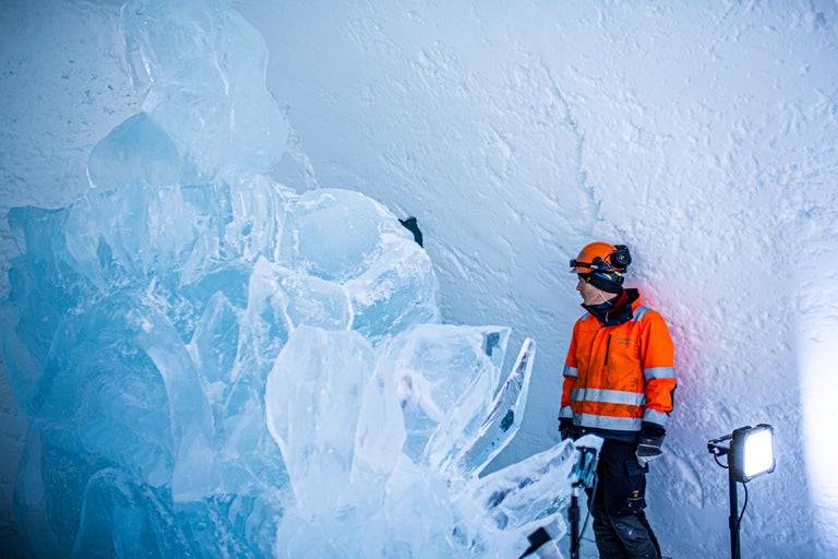 Homme avec casque de sécurité et veste de signalisation dans une grotte de glace