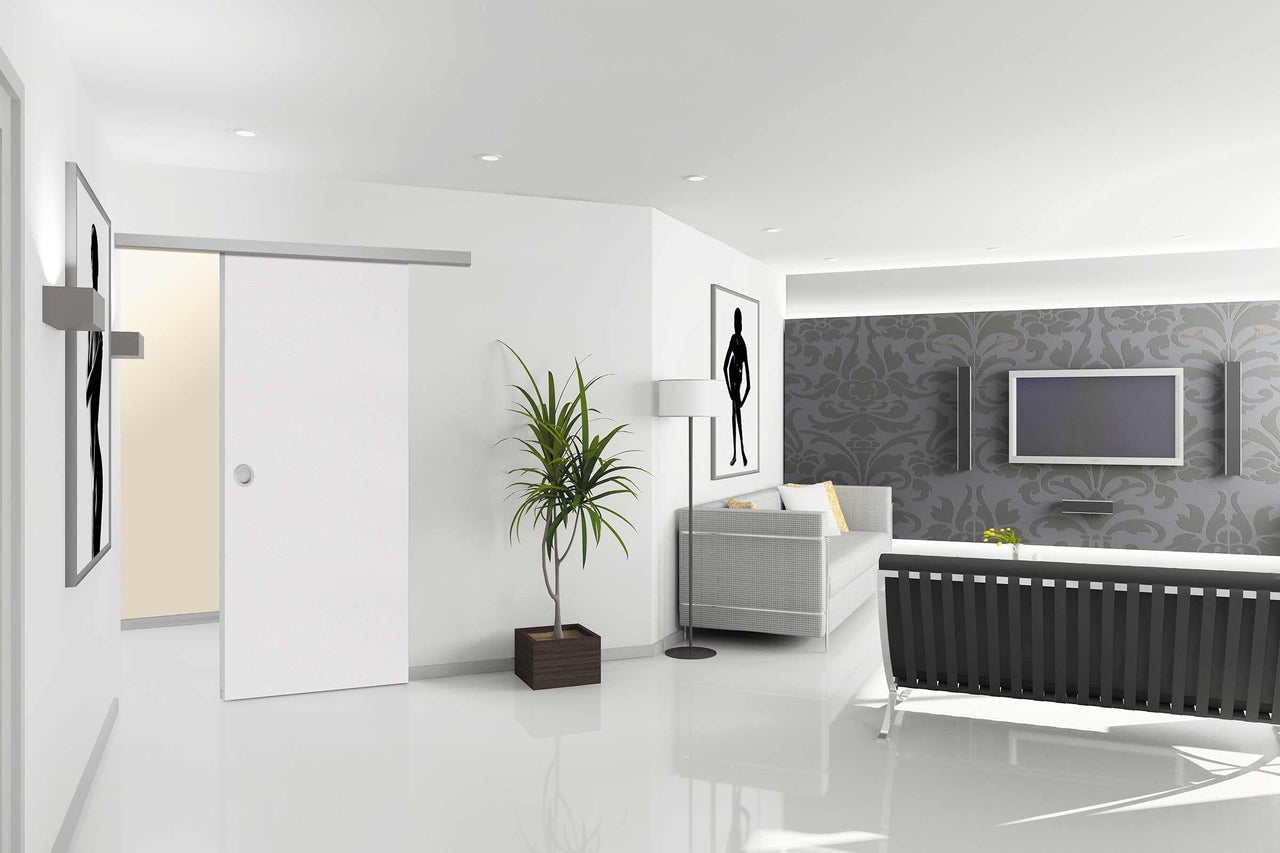 Helles Wohnzimmer mit Schiebetür, Pflanze und grauer Couch vor einer gemusterten Wand