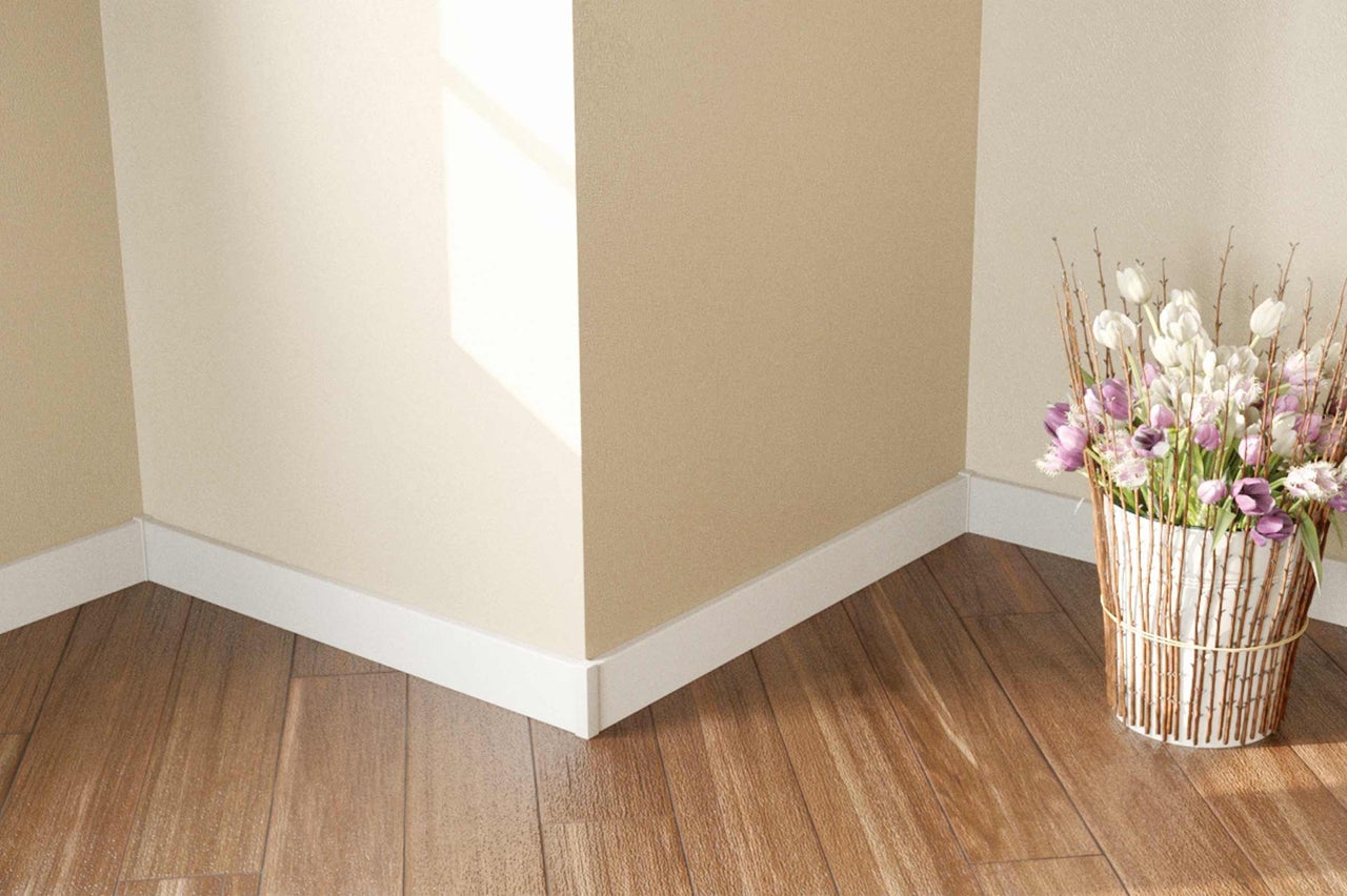 Eckansicht eines Raumes mit Holzboden, weissen Fussleisten und einer Blumenvase