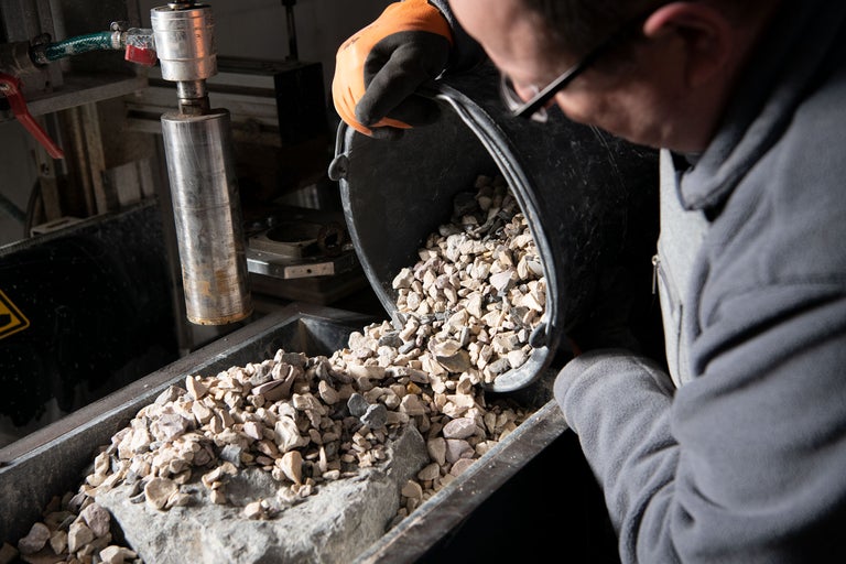 Une personne verse du gravier d'un seau dans un récipient.
