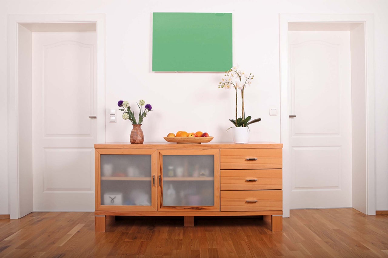 Salon avec commode en bois, deux portes et une image verte