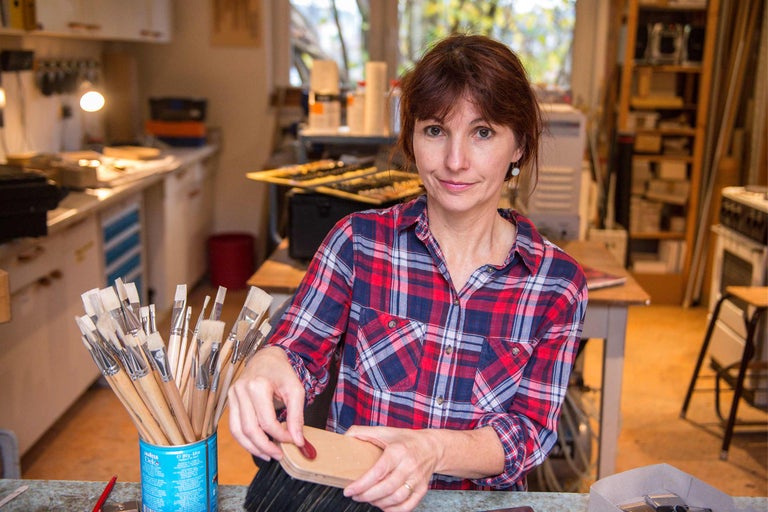 Frau reinigt Pinsel mit Pinselreinigungsseife in einer Werkstatt.