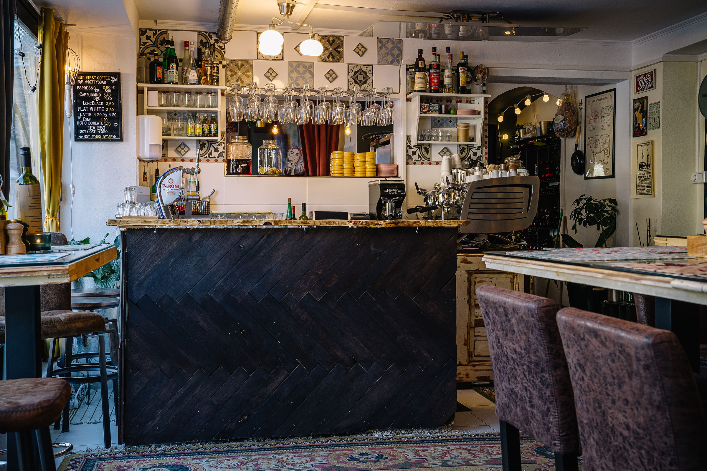 Vue intérieure d'un café avec comptoir, étagères et tables.