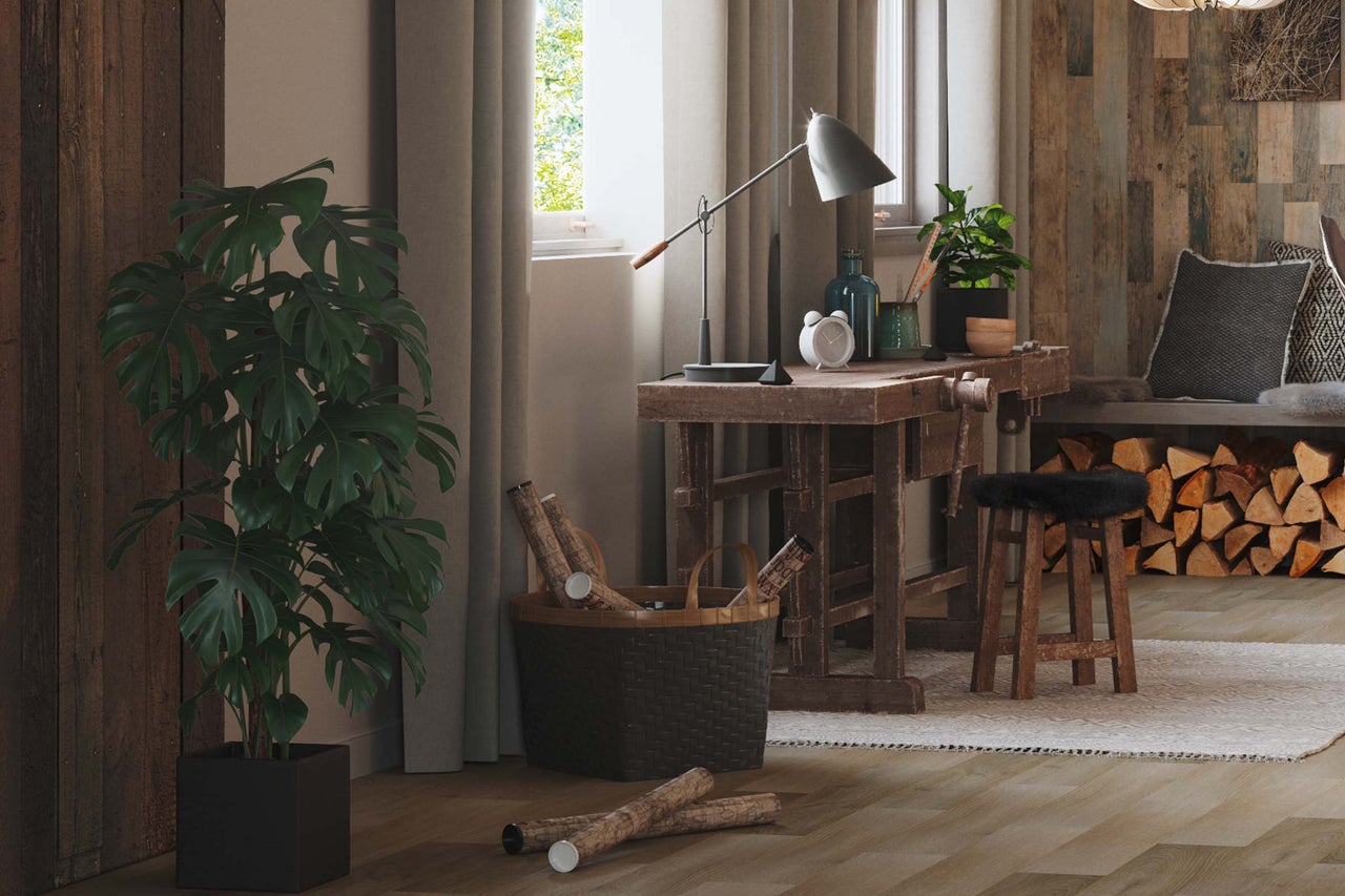 Salon lumineux avec parquet en bois, table de travail, plante d'intérieur et bois de cheminée