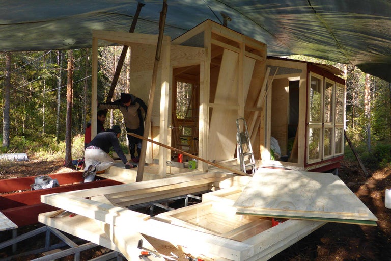 Bauarbeiten an einem Holzhaus im Freien mit mehreren Personen