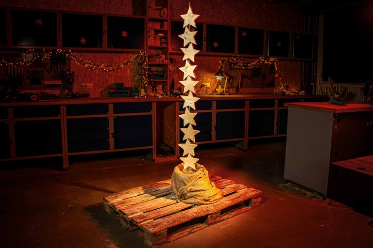 Werkstattdekoration mit Holzsternen auf Palette und Lichterkette im Hintergrund.
