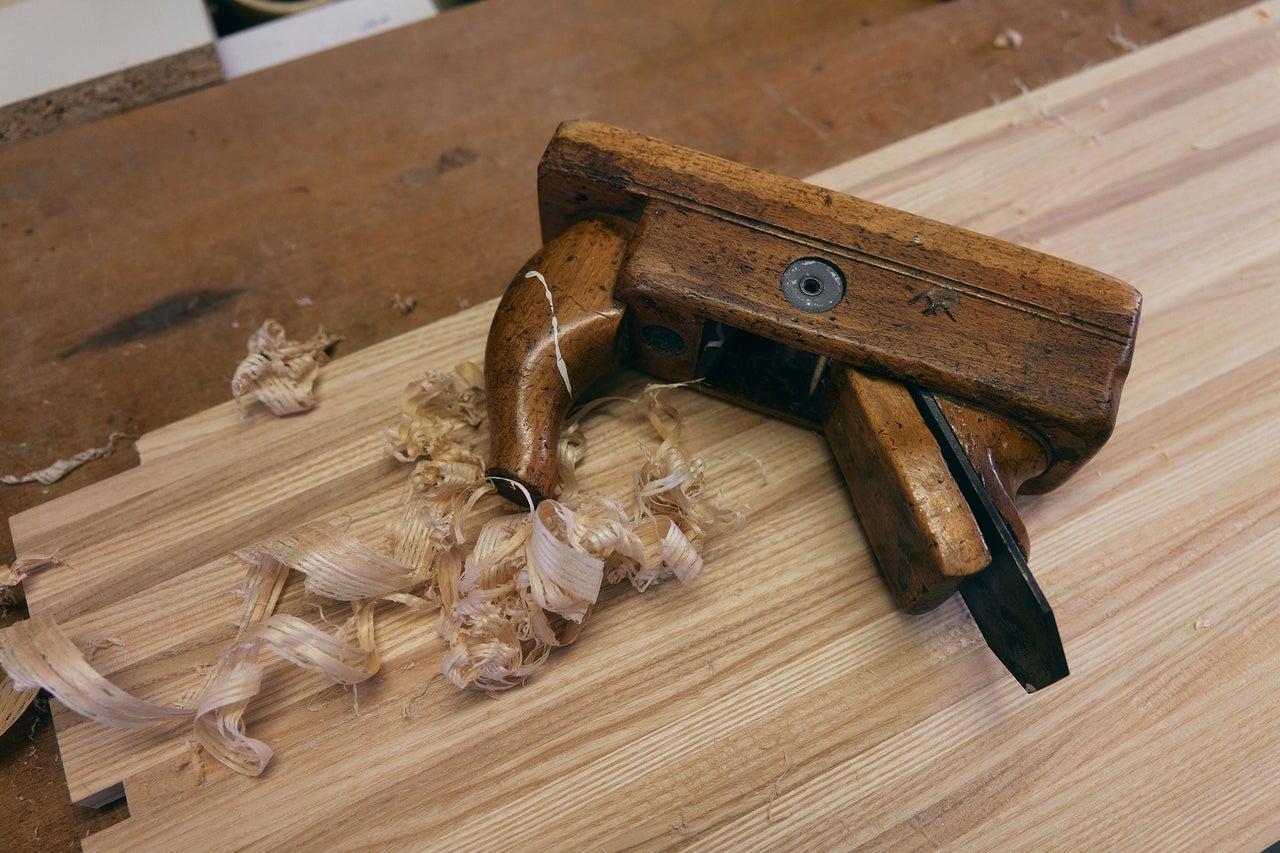 Hobel aus Holz mit Holzspänen auf einem Holzbrett