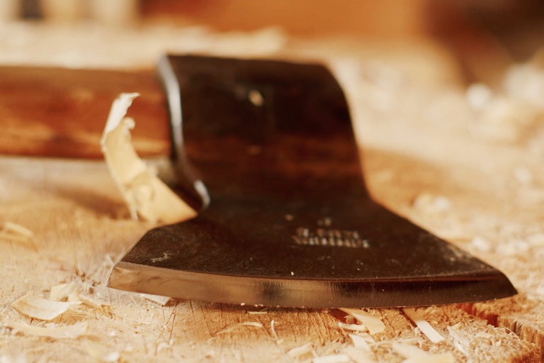 Gros plan d'une hache sur un morceau de bois avec des copeaux de bois