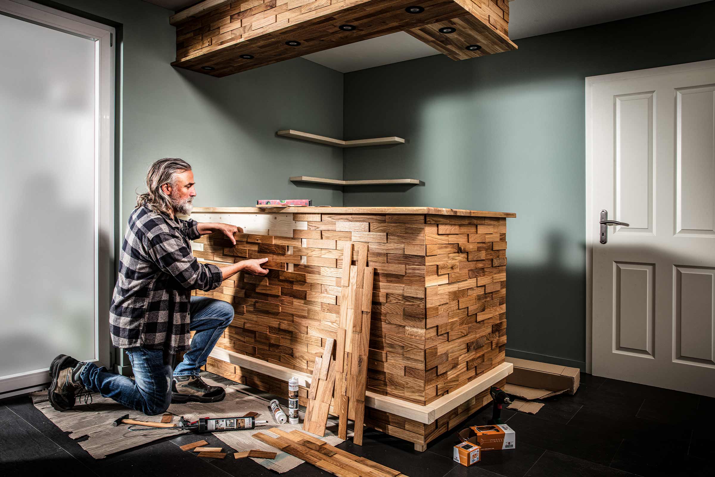Mann verkleidet eine Bar mit Holzpaneelen im Innenbereich, helle und organisierte Atmosphäre.