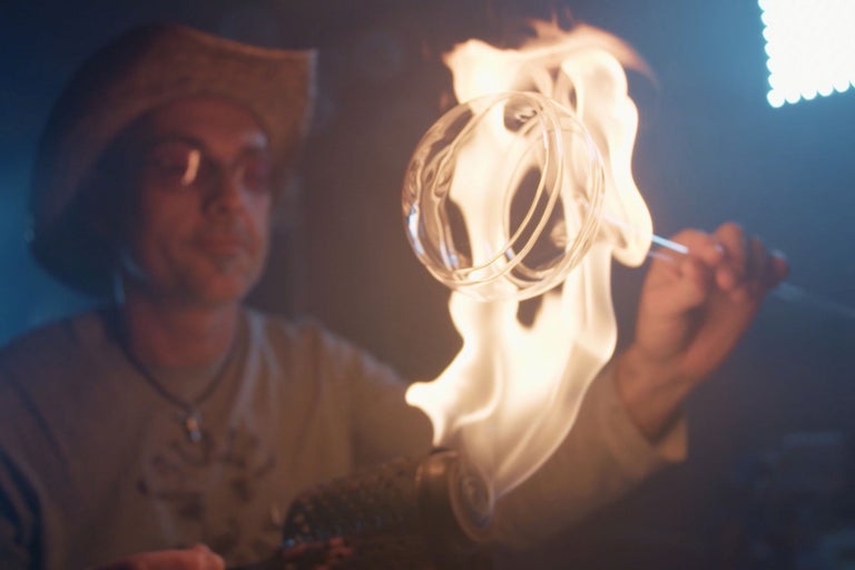Ein Glasbläser formt Glas mit einer Flamme.
