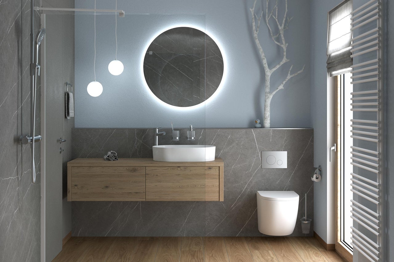 Salle de bain moderne avec meuble sous-vasque aspect bois, vasque à poser, miroir rond éclairé, toilette suspendue et douche à l'italienne.