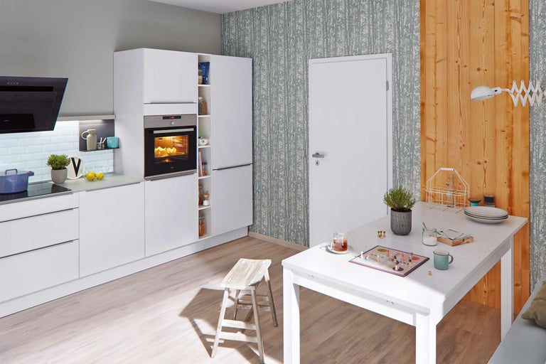 Coin cuisine lumineux avec meubles blancs, table à manger et chaise.