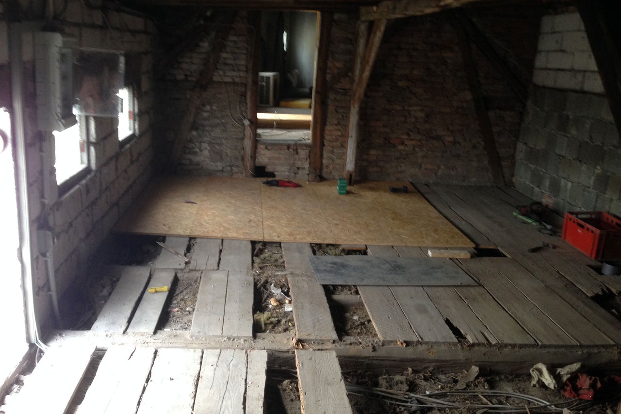 Un grenier avec des poutres en bois et un plancher en bois partiellement posé