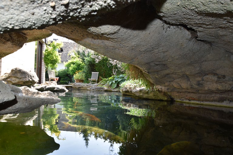 Bassin avec rochers et mobilier de jardin en arrière-plan