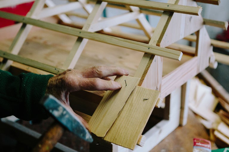 Artisan clouant une construction en bois.