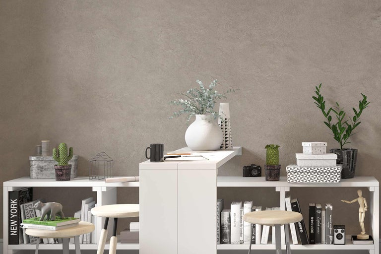 Pièce avec des étagères blanches, des tabourets, des plantes d'intérieur et des objets de décoration devant un mur