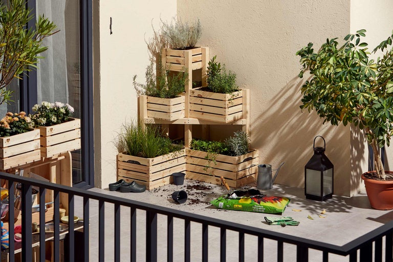 Scène de balcon avec des jardinières en bois, des outils de jardinage et des plantes