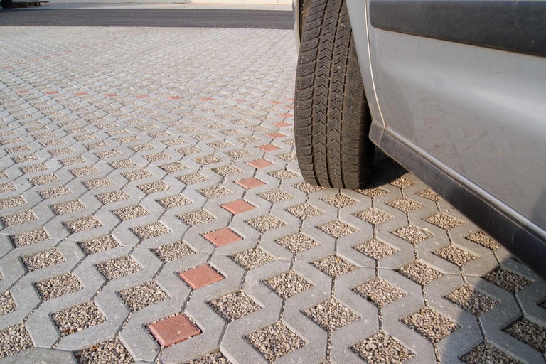 Dalles alvéolées avec remplissage de gravier à côté d'une voiture