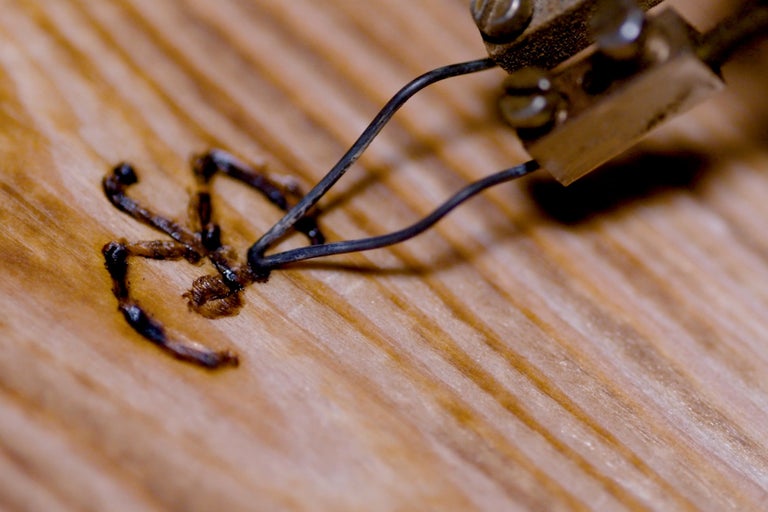 Gros plan d'un fer à souder décorant du bois