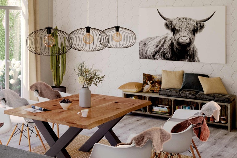 Esszimmer mit Holztisch, Pendelleuchten und Kuhbild an der Wand.