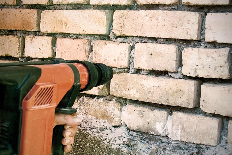 Eine Bohrmaschine bohrt ein Loch in eine Ziegelwand.