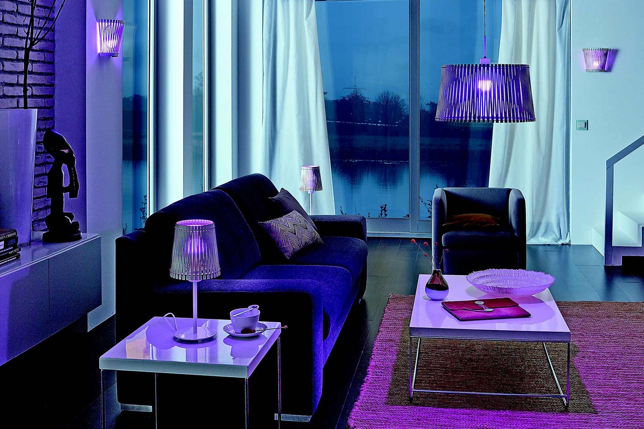 Wohnzimmer mit Sofa, Sessel, Couchtisch und verschiedenen Lampen für eine gemütliche Atmosphäre