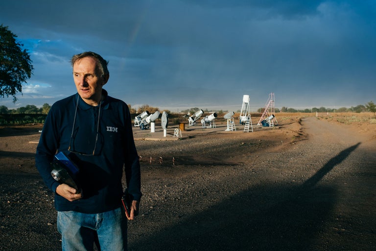 Mann steht auf einem Feld mit Teleskopen im Hintergrund