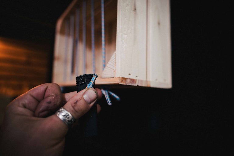 Une personne utilise un briquet pour fixer une corde à une étagère en bois.