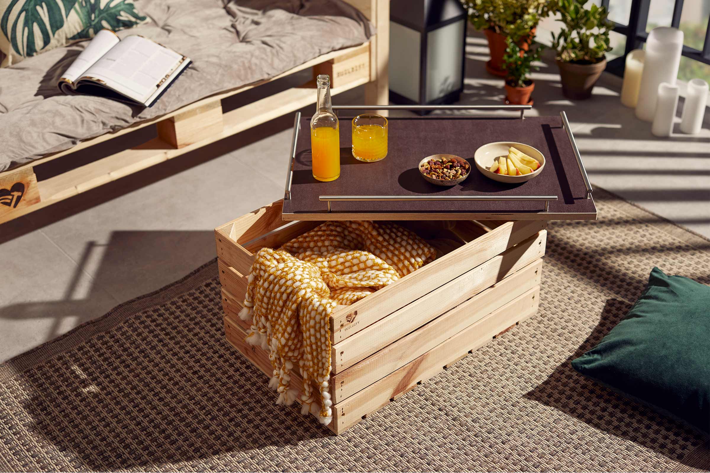 Wohnszene mit Möbeln aus Holzpaletten, Getränken und Snacks auf einem Tablett