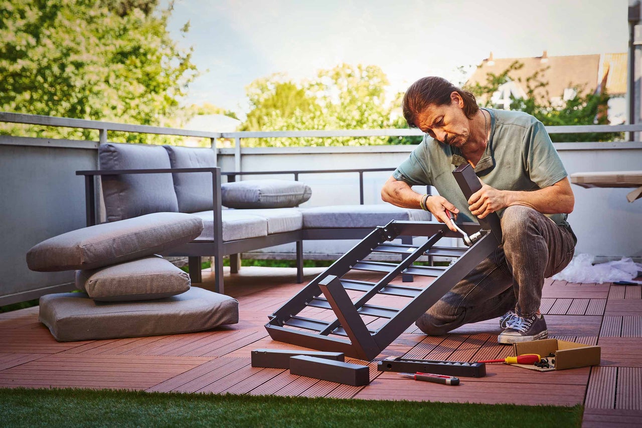 Femme ponçant une planche de bois à l'extérieur avec une cale à poncer sur un établi