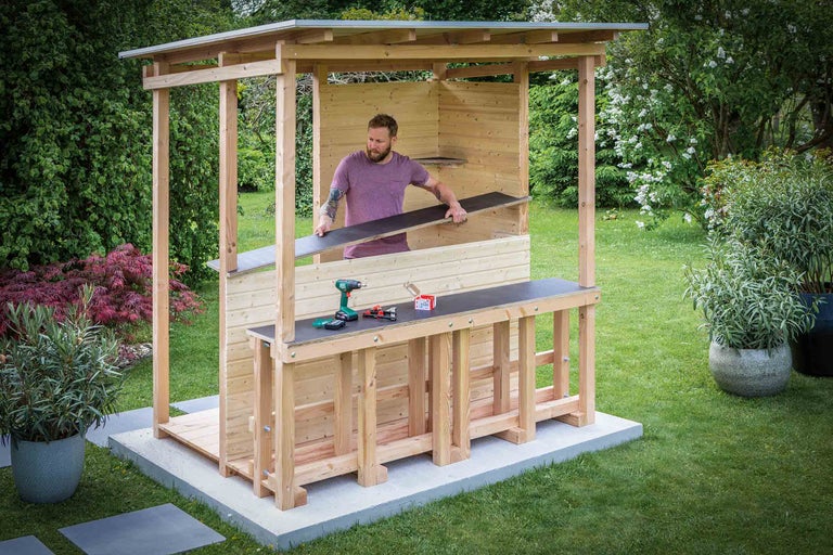 Person montiert eine Holzgartenbar mit Werkzeugen