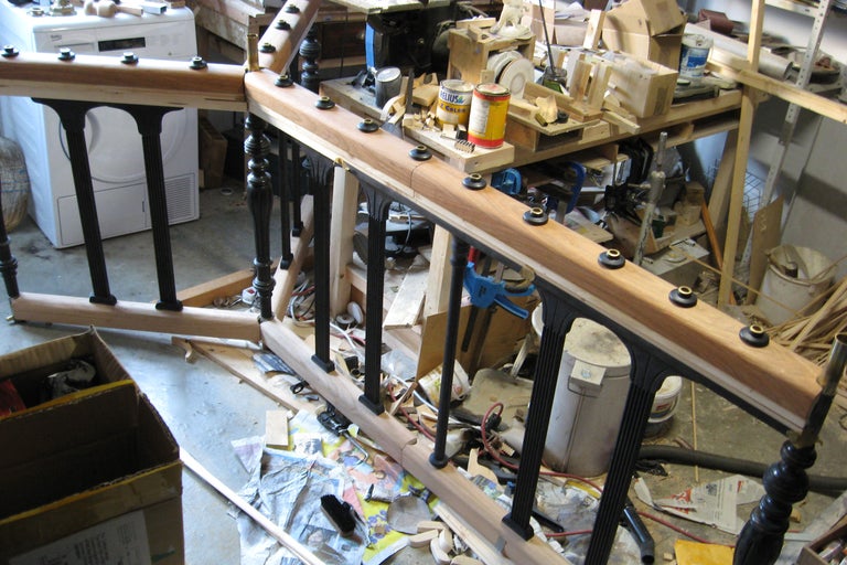 Garde-corps en bois non fini avec barreaux noirs dans un atelier.