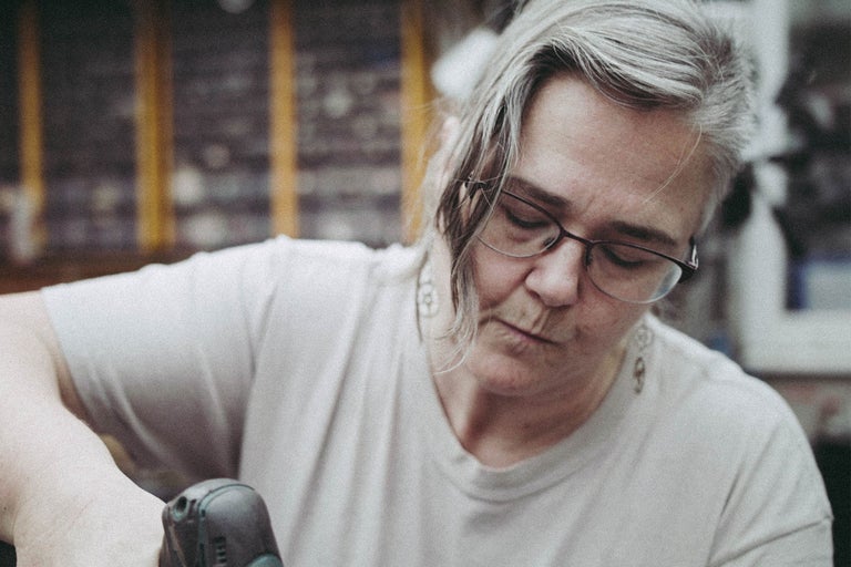 Femme portant des lunettes travaillant avec une visseuse sans fil.
