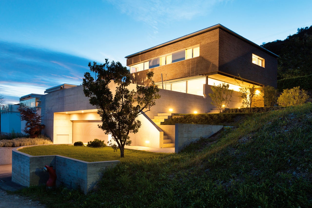 Maison moderne avec garage, jardin et éclairage extérieur au crépuscule