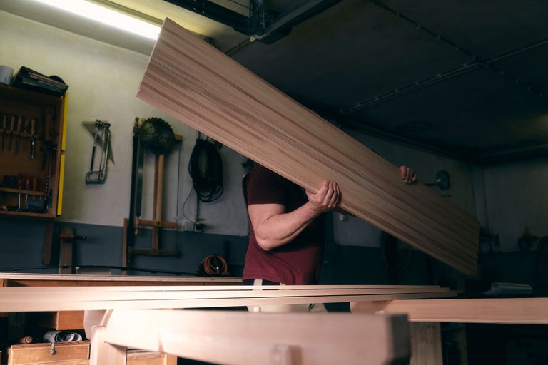 Artisan portant une planche de bois dans un atelier