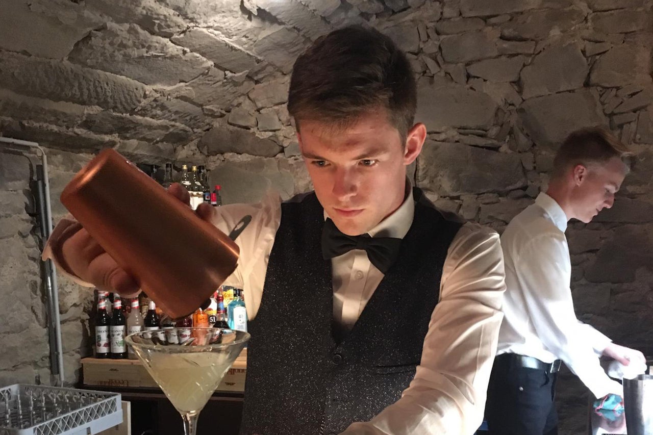 Ein Barkeeper giesst einen Cocktail in einem Glas aus einem Shaker